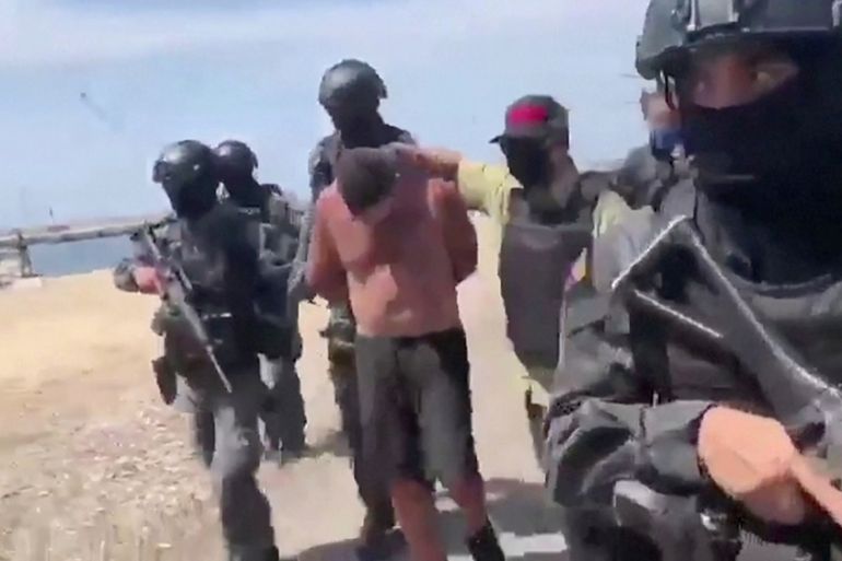 Venezuelan soldiers in balaclavas move a suspect from a helicopter after what Venezuelan authorities described was a "mercenary incursion", at an unknown location in this still frame obtained from Ven