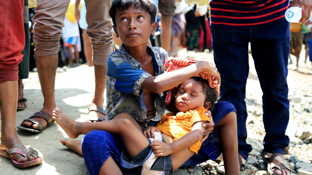 A Rohingya boy cradles his unconscious younger sister. Their father was killed and they became separated from their mother as they fled Myanmar [Showkat Shafi/Al Jazeera]