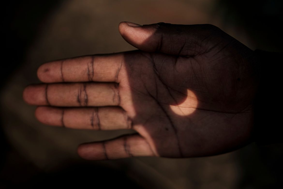 The partial solar eclipse is projected on a Kenyan man''s hand through binoculars in Nairobi, Kenya on June 21, 2020. (Photo by YASUYOSHI CHIBA / AFP)