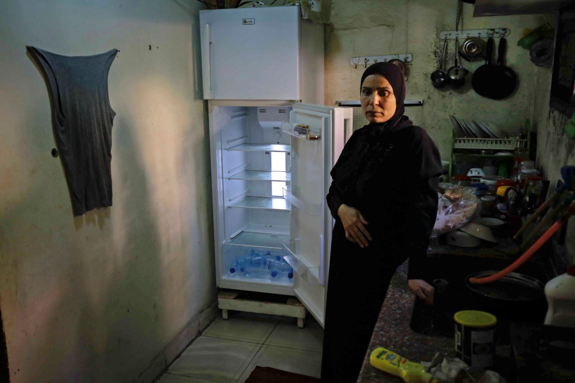 A Lebanese woman stands next to her empty refrigerator in her apartment in the port city of Tripoli north of Beirut on June 17, 2020. - Lebanon''s economic crisis has led to a collapse of the local cur