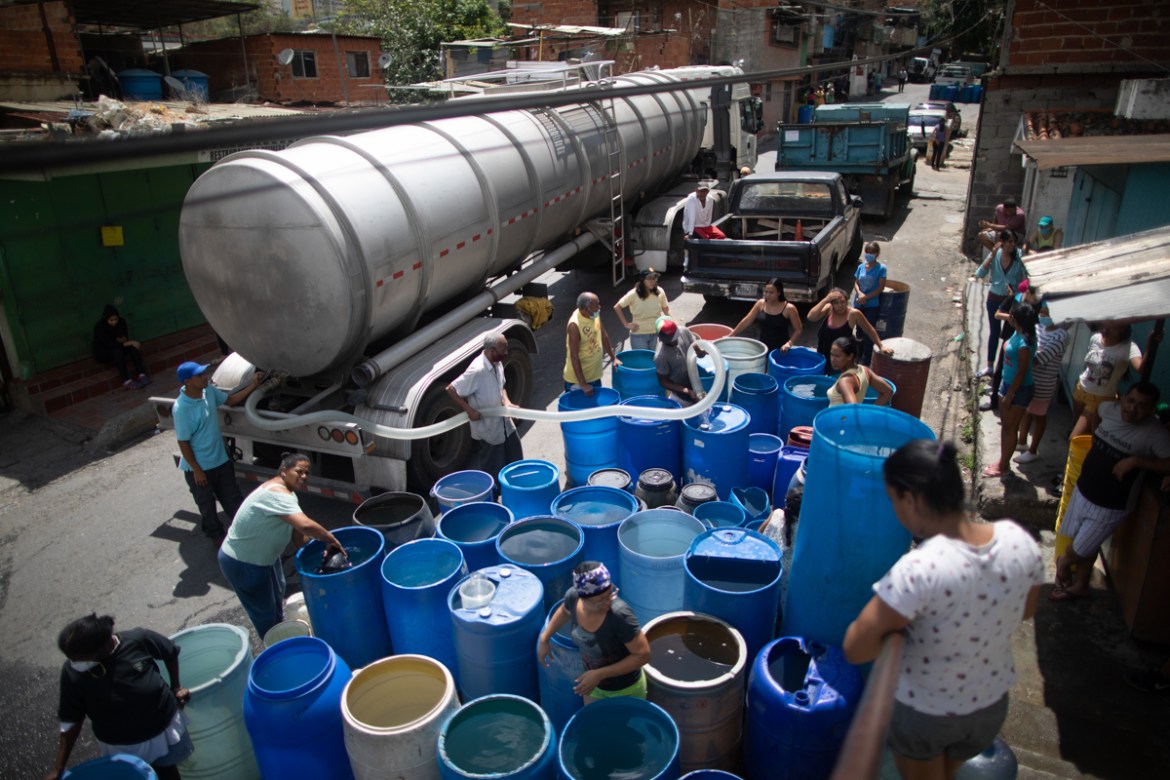 Residents fill their containers with water provided by a government tanker truck in the Petare neighborhood of Caracas, Venezuela, Monday, June 15, 2020. Water shortages have continued to deepen in Ve