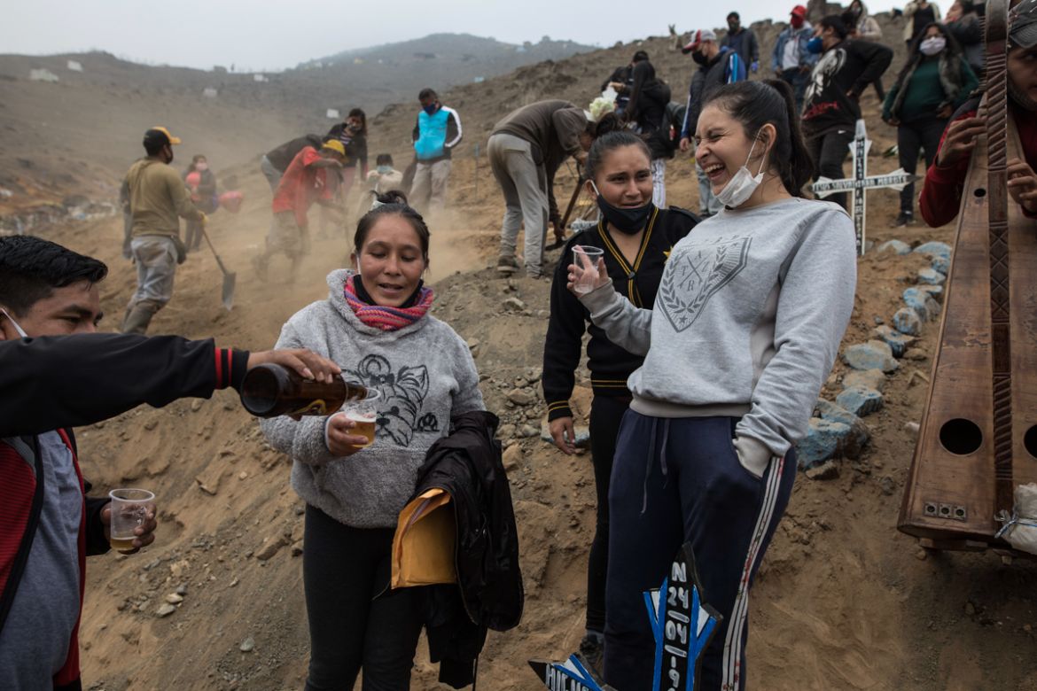 Relatives of brothers Jorge Zumaeta, 50, and Miguel Zumaeta, 54, who died of COVID-19, drink beer and joke during their burial at the Nueva Esperanza cemetery on the outskirts of Lima, Peru, Tuesday,