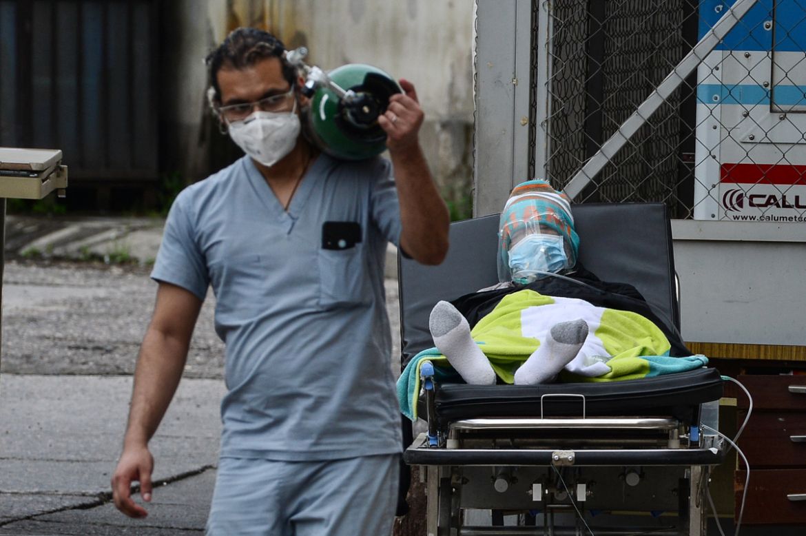 A doctor carries an oxygen tank after disconnecting a man infected with COVID-19 from it at a field hospital set up in the yard of the School Hospital in Tegucigalpa on June 17, 2020. - The authoritie