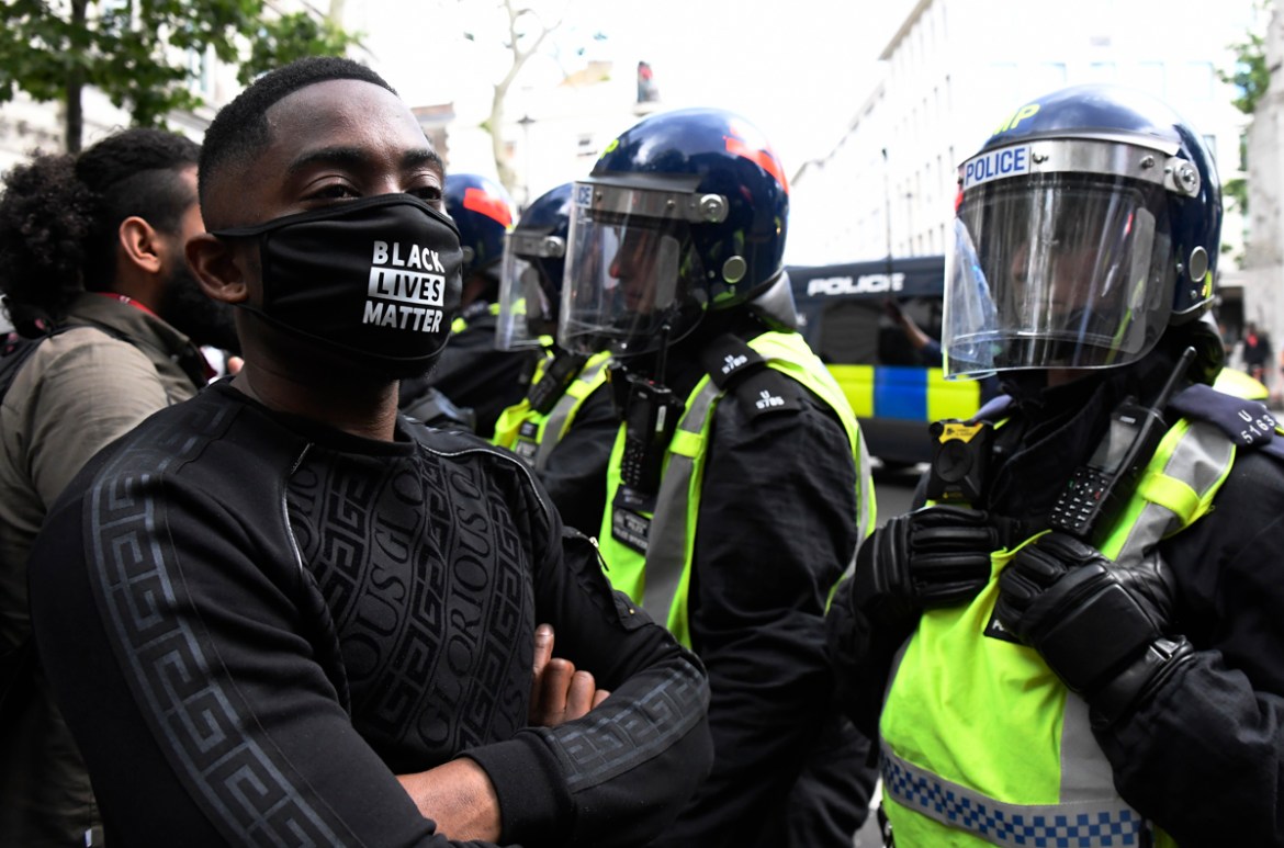 A wounded member of a far-right group is escorted by British police officers in riot gear, during scuffles as they try to contain a protest at Trafalgar Square in central London, Saturday, June 13, 20