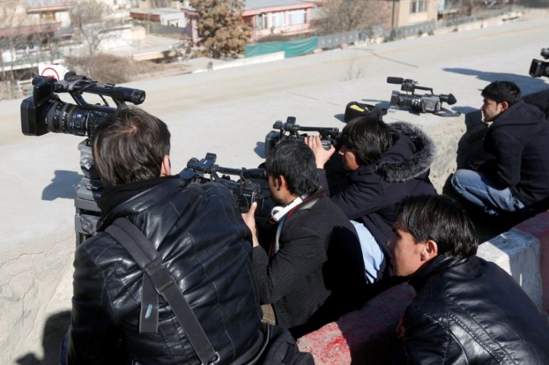 Afghan journalists take cover as they film the site of an attack by gunmen in Kabul