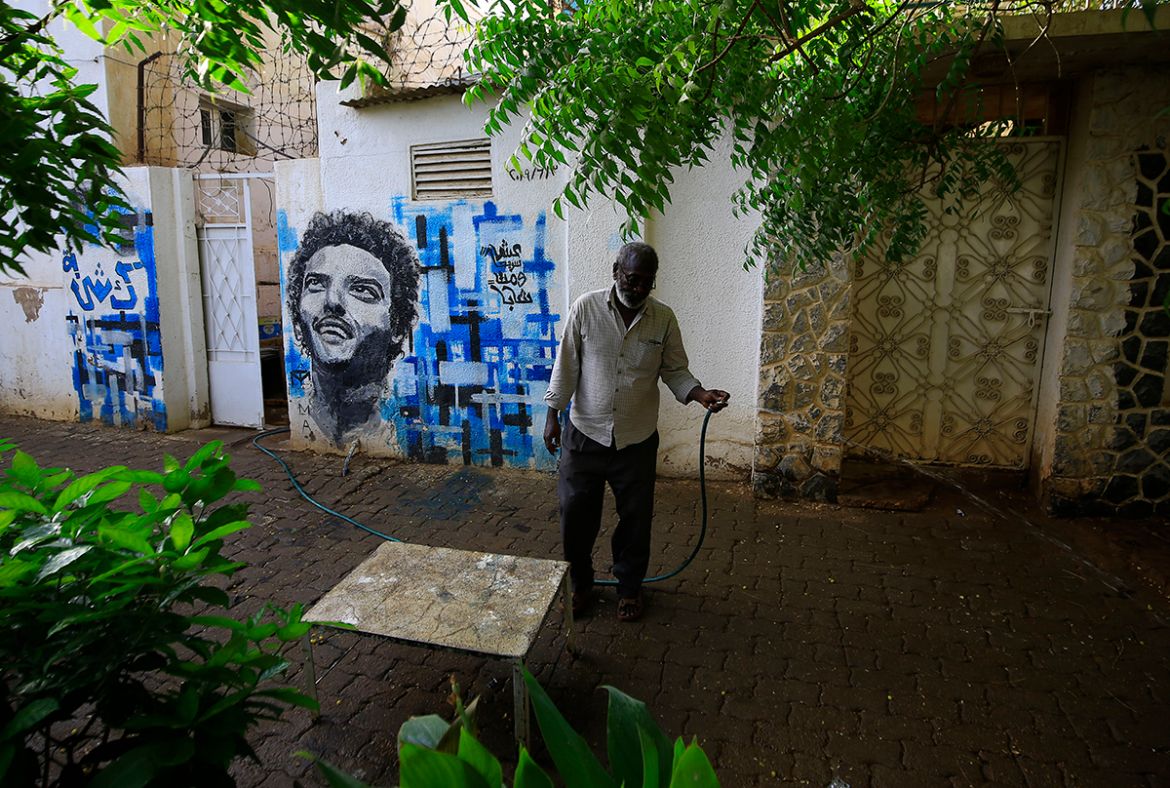 Sudanese Kisha Abdulsalam waters plants near a mural depicting his late son Abdulsalam on June 2, 2020 in Khartoum on the eve of a raid where at least 128 people were killed and hundreds wounded outsi