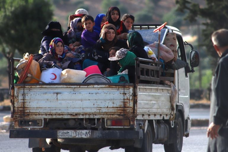 Displaced Syrians sit in the back of a truck loaded with belongings as they flee along the M4 highway, in Ariha in the rebel-held northwestern Syrian province of Idlib, on June 8, 2020, heading north.