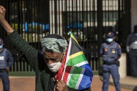 A woman holds a South African national flag during a protest against racism in front of the US Embassy in Pretoria, South Africa on June 5, 2020 [AP/Themba Hadebe]