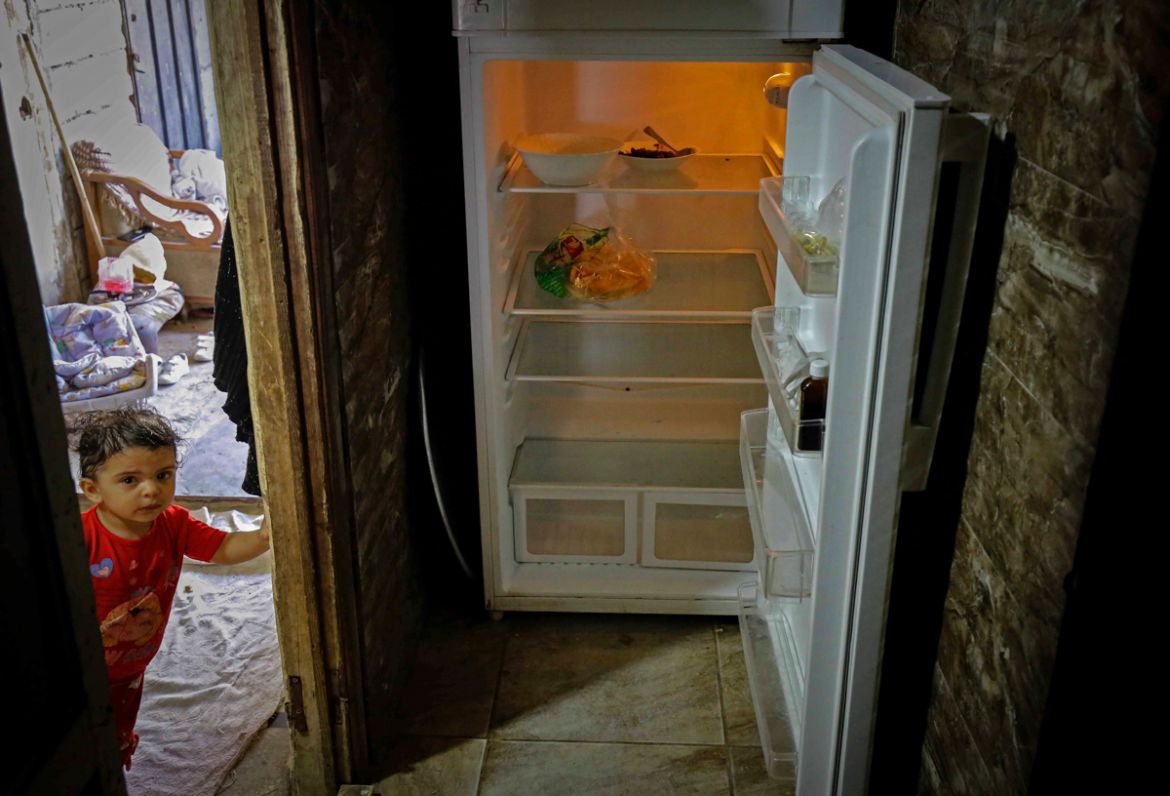 A Lebanese child stands next to an empty refrigerator in their apartment in the port city of Tripoli north of Beirut on June 17, 2020. - Lebanon''s economic crisis has led to a collapse of the local cu