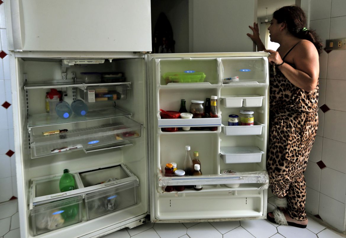 A Lebanese woman displays the content of her refrigerator at her apartment in Jounieh, north of the capital Beirut, on June 19, 2020. - Lebanon''s economic crisis has led to a collapse of the local cur