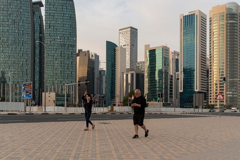 People walk in West Bay area in Doha, Qatar, March 25, 2020. Qatar has imposed a series of measures to contain the coronavirus outbreak, including closing of parks and public areas, banning social gat