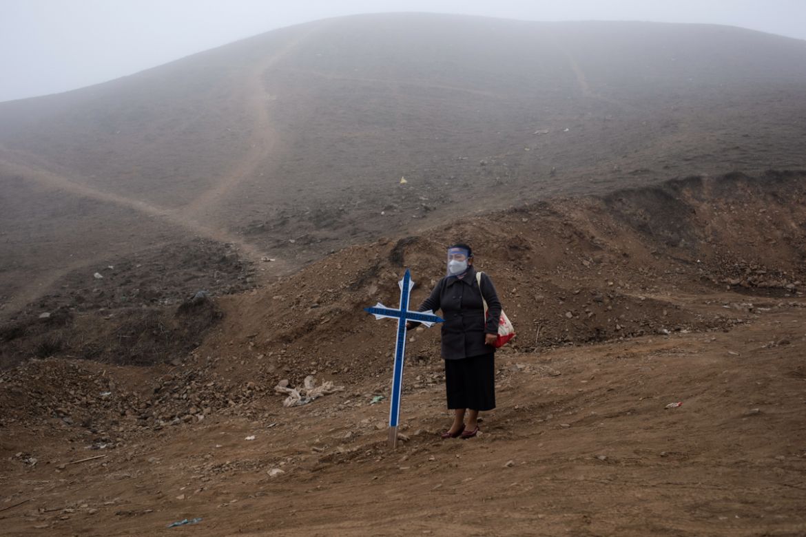 Noly Suarez holds a cross during the burial of her brother Flavio Juarez, 50, who died of COVID-19, at the Nueva Esperanza cemetery on the outskirts of Lima, Peru, Tuesday, May 26, 2020. (AP Photo/Rod