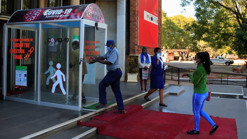A policeman washes his hands as he enters a sanitizing booth during a nationwide lockdown to help curb the spread of the coronavirus disease (COVID-19) at a court in Harare
