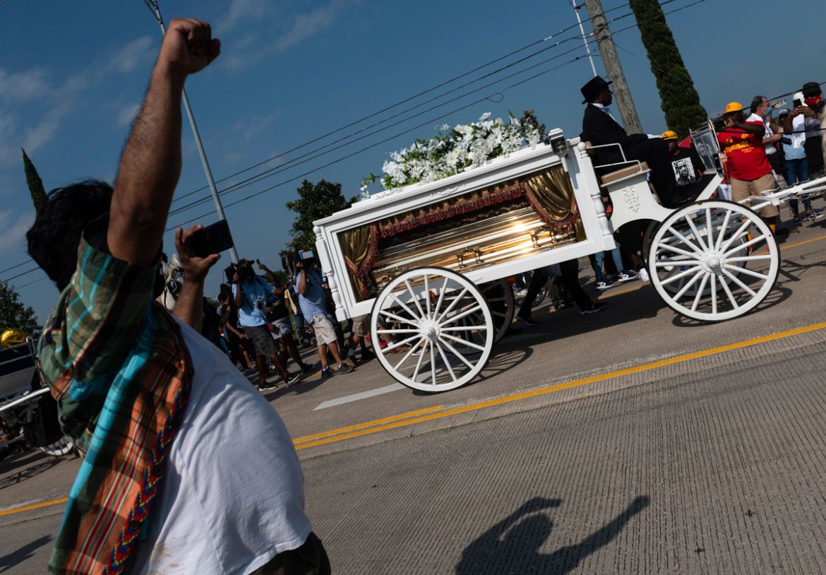 A man raises his fist as mourners watch the casket of George Floyd carried by a white horse-drawn carriage to his final resting place at the Houston Memorial Gardens cemetery in Pearland, Texas on Jun
