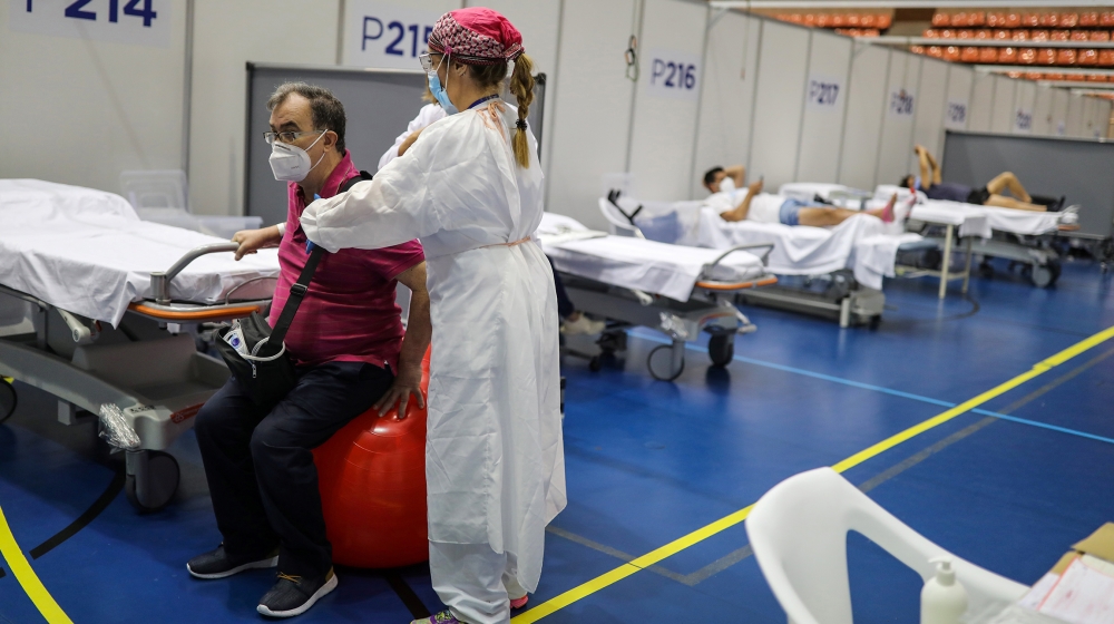 Daniel Catey, 62, a recovered COVID-19 patient, undergoes rehabilitation with a physical therapist at the Hospital Vall d'Hebron facility, a hastily converted sports centre, in Barcelona, Spain, June 
