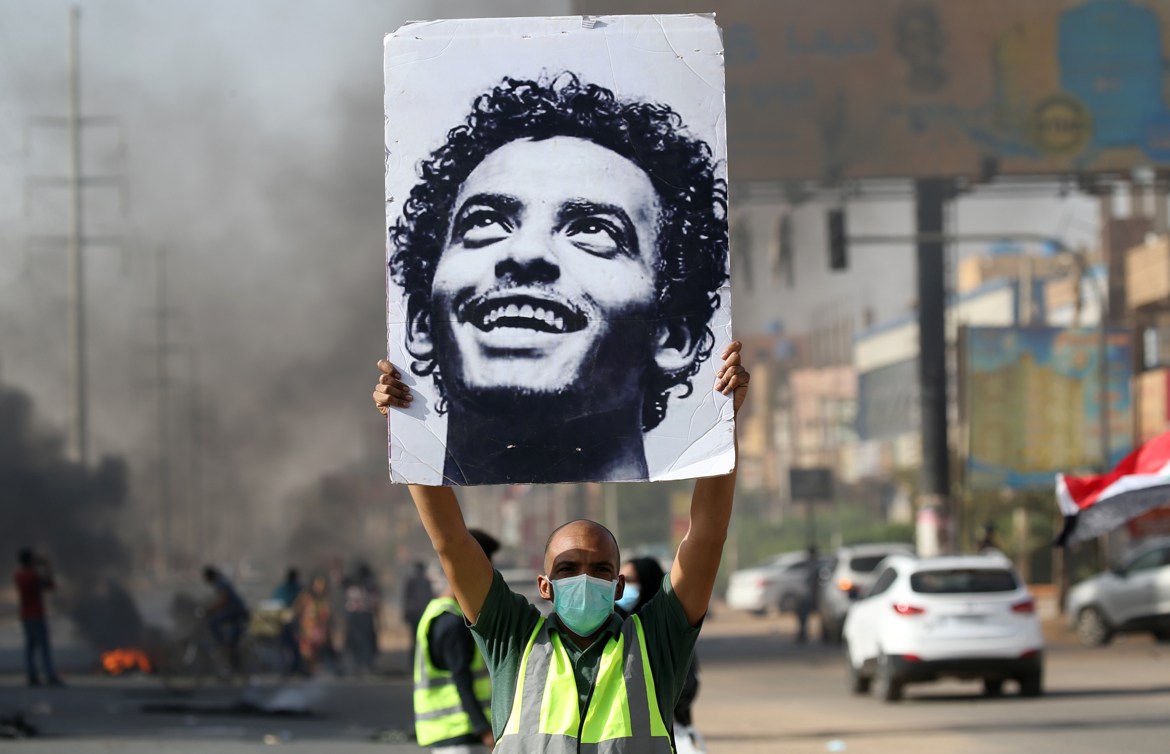 A mask-clad man holds a picture of a Abdulsalam Kisha, a Sudanese protester who was killed in a raid on an anti-government sit-in in 2019, during a protest in the Riyadh district in the east of the ca