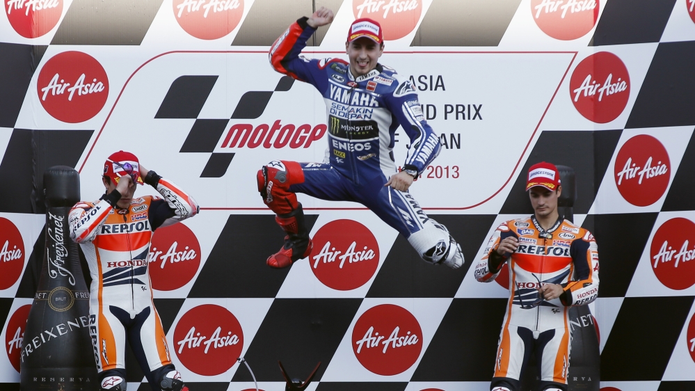 Yamaha MotoGP rider Lorenzo of Spain jumps into the air as he celebrates winning the Japanese Grand Prix next to Honda MotoGP rider Marquez of Spain and Pedrosa of Spain on the podium in Motegi