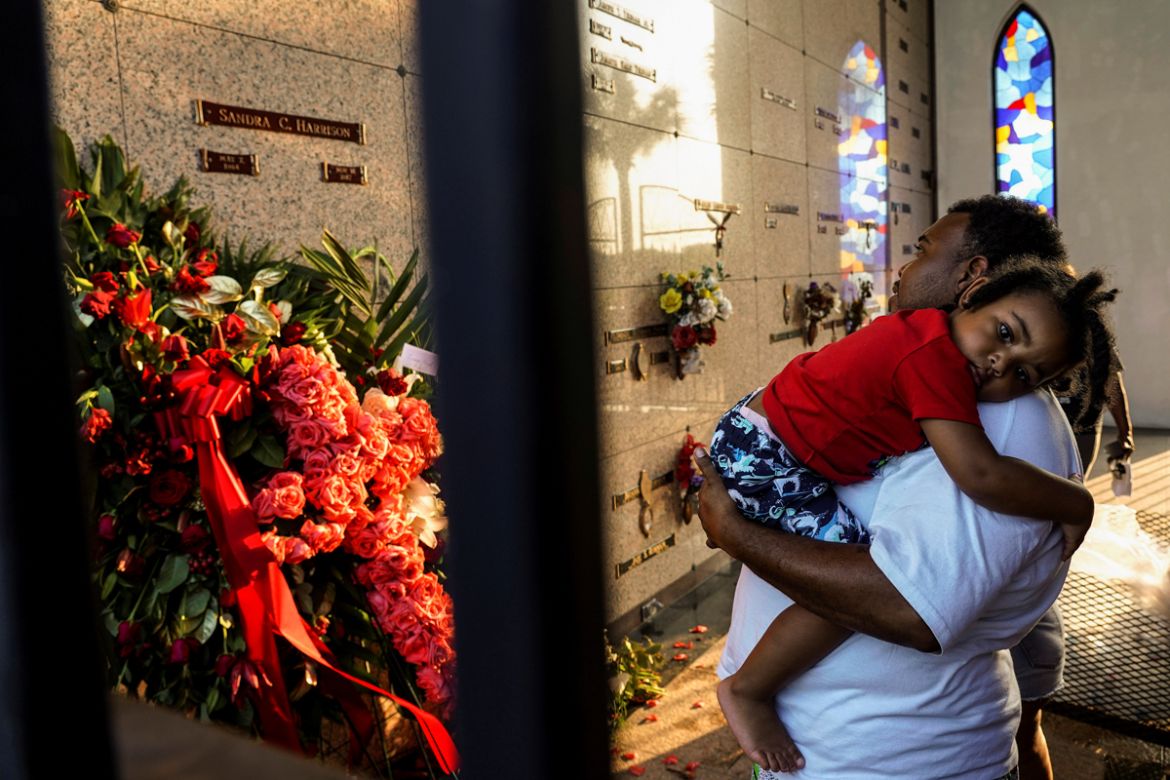A mourner carries a child as he pays respects at Houston Memorial Gardens cemetery where George Floyd was buried, whose death in Minneapolis police custody has sparked nationwide protests against raci
