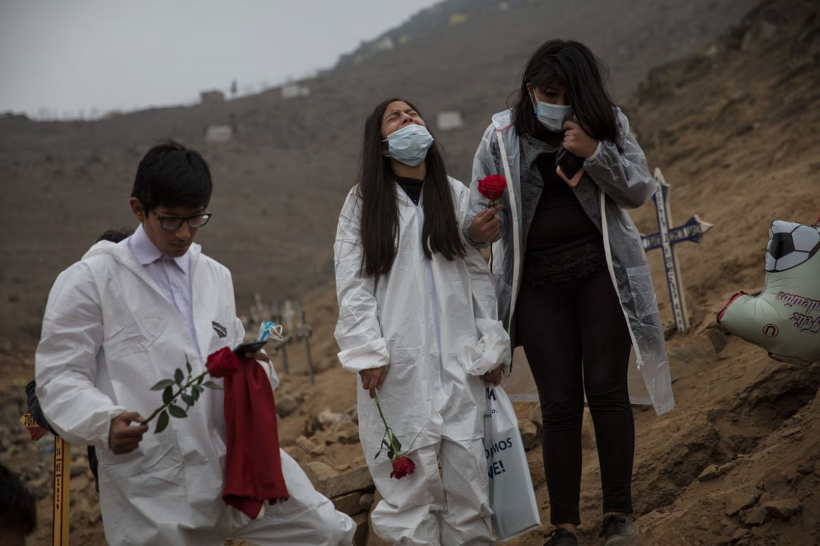 Dayra Montalbo, 12, center, cries, next to her sister Valeria, 18, and his brother Carlos, 16, during the burial of their father Carlos Montalbo, 45, who died from COVID-19 complications, at the Nueva