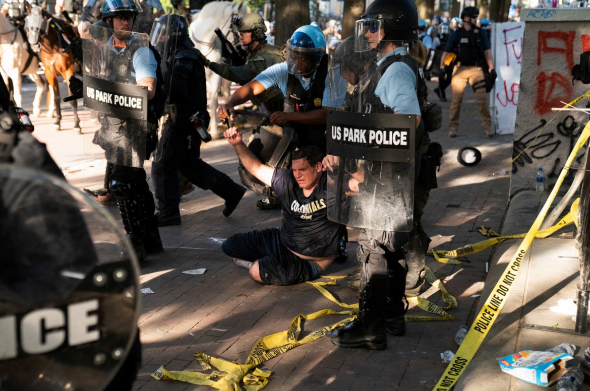 Riot police detain a man as they rush protestors to clear Lafayette Park and the area around it across from the White House for President Donald Trump to be able to walk through for a photo opportunit