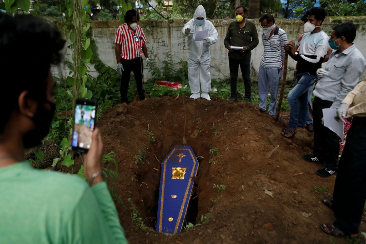 A priest wearing personal protective equipment (PPE) prays over the coffin of a person who died from the coronavirus disease (COVID-19) during a funeral at a cemetery in Mumbai, India June 27, 2020. R