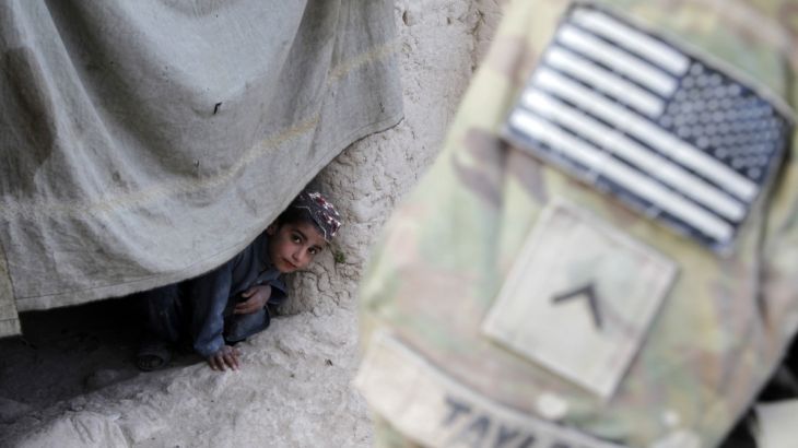 An Afghan boy watches a U.S. soldier on patrol in Zharay district in Kandahar province, southern Afghanistan