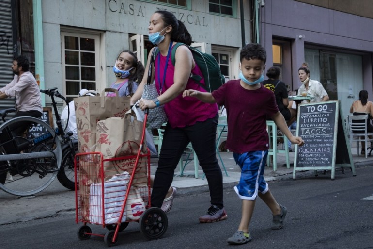 Pedestrians pass customers dining outside Casa Mezcal, Monday, June 22, 2020, in New York. New York City ventured into a crucial stage of reopening as stores let people in Monday, offices brought work
