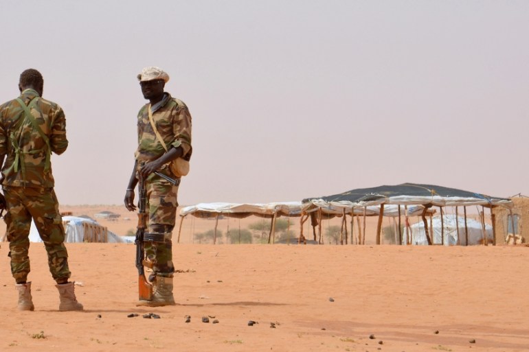 Niger soldiers stand guard during a visit by the Interior Minister Mohamed Bazoum on October 21, 2016 to the in Tazalit United Nations refugee camp in the Tahoua region some 300 kilometres northeast o