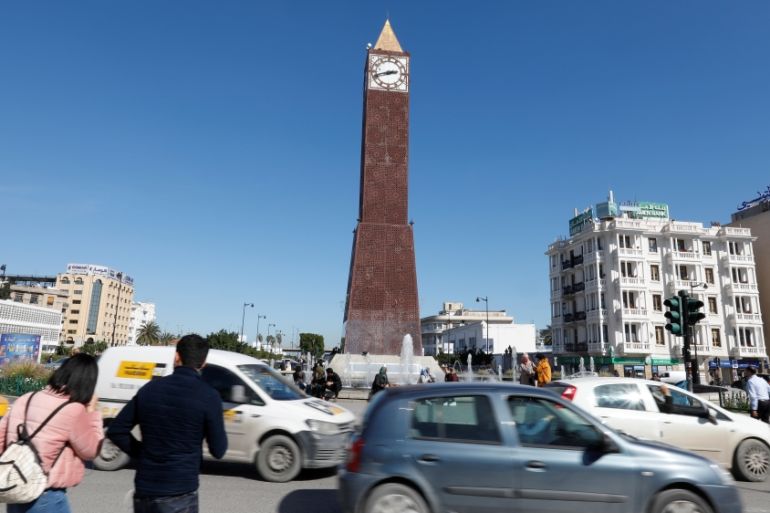 Cars and people pass by the clock tower at the end of Avenue Habib Bourguiba in Tunis