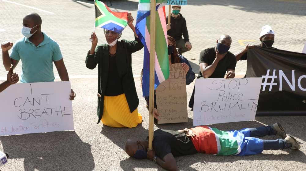Protesters hold placards as they demonstrate against the death in Minneapolis police custody of George Floyd and Collins Khoza, in Pretoria