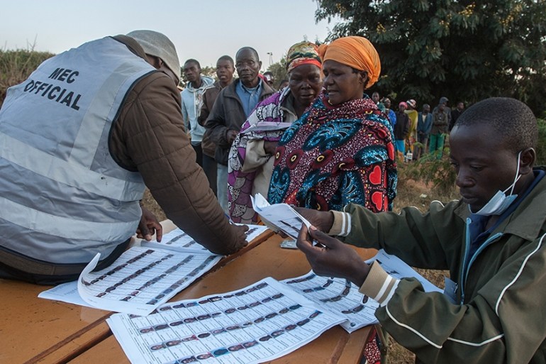 Electoral officials check the voters roll while people queue to vote at the Malembo polling station during the presidential elections in Lilongwe on June 23, 2020. - Malawians return to the polls on J