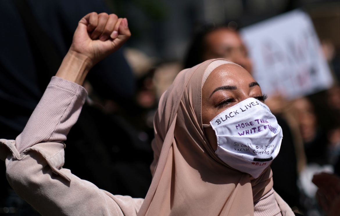 A woman wearing a face mask raises her fist during a protest against the death in Minneapolis police custody of African-American man George Floyd, at Hermannplatz square in Neukoelln district, Berlin,