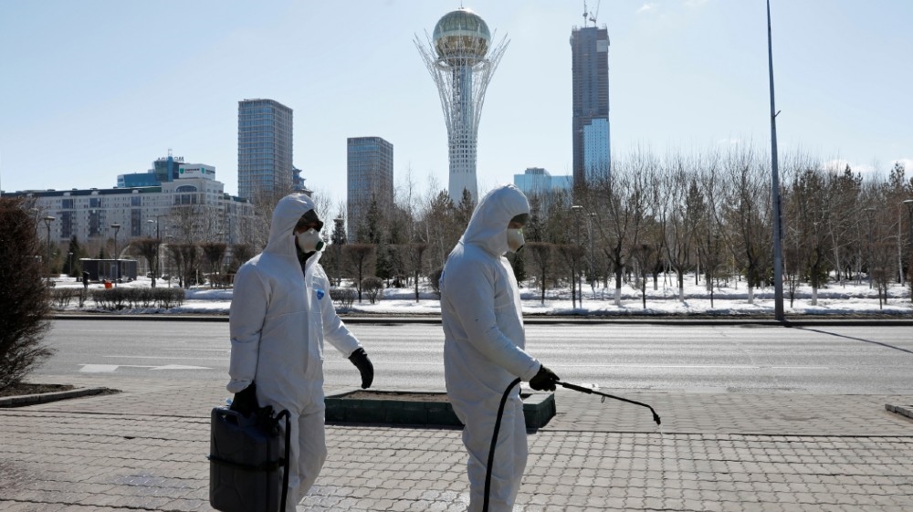 Workers wearing protective suits spray disinfectant on the street to prevent the spread of coronavirus disease (COVID-19), in central Nur-Sultan, Kazakhstan March 24, 2020. 