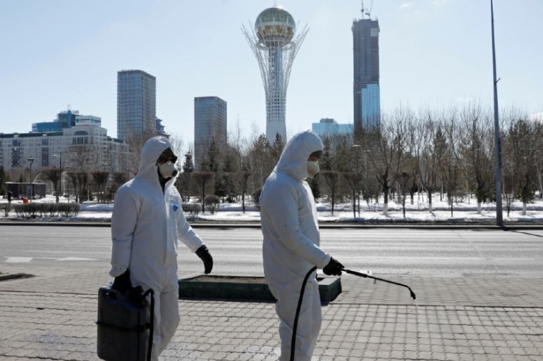 Workers wearing protective suits spray disinfectant on the street to prevent the spread of coronavirus disease (COVID-19), in central Nur-Sultan, Kazakhstan March 24, 2020.