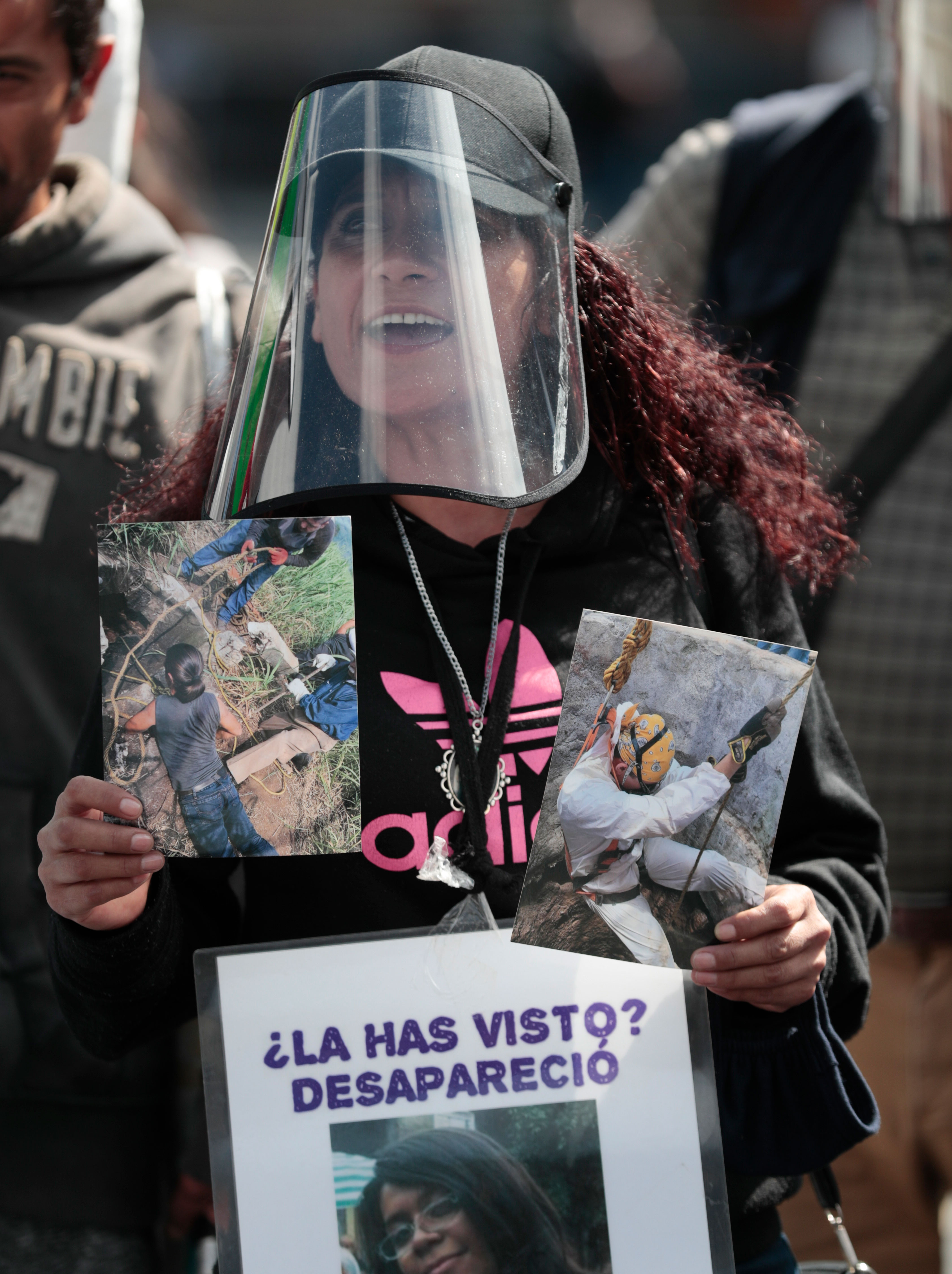
A woman wearing a mask amid the coronavirus pandemic holds an image of a person who was disappeared, during a protest in front of the National Palace in Mexico City [Eduardo Verdugo/AP Photo]
