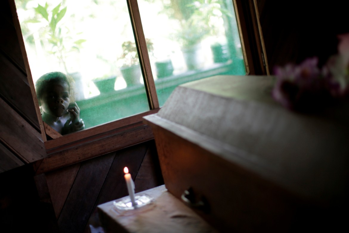 A child looks through the window as the coffin holding Andrelina Bizerra da Silva, 49, who died on the way to a health clinic after she experienced days of suffering from shortness of breath and then