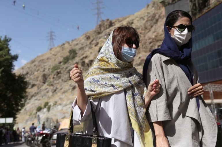Iranian women wearing protective face masks walk in Darband street