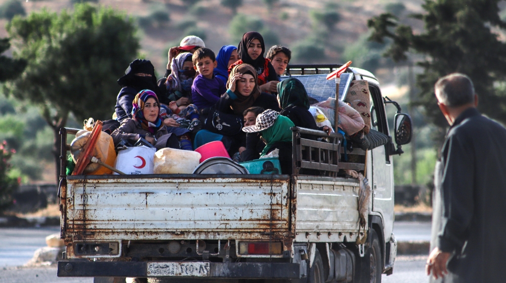Displaced Syrians sit in the back of a truck loaded with belongings as they flee along the M4 highway, in Ariha in the rebel-held northwestern Syrian province of Idlib, on June 8, 2020, heading north.