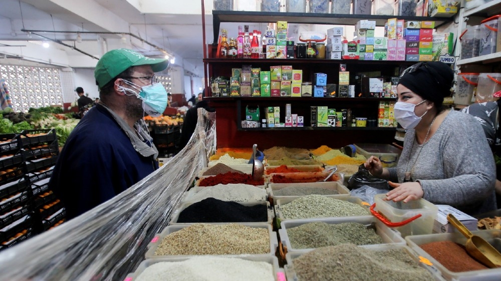 A vendor wearing a protective face mask serves a customer inside her shop, ahead of the Muslim holy month of Ramadan, amid concerns over the coronavirus disease (COVID-1