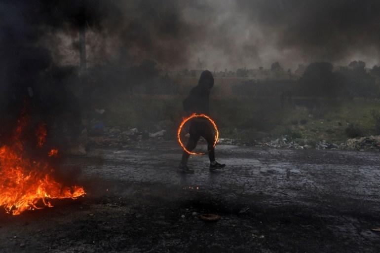 Palestinian demonstrator holds a ring of fire during clashes with Israeli forces at a protest marking Land Day, near the Jewish settlement of Beit El, in the Israeli-occupied West Bank