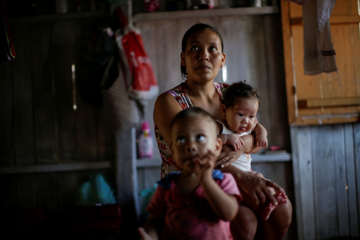 Maria de Jesus, 36, sits with her children in her home at the riverside community Galileia, as she reacts to being told by healthcare workers that she has tested positive for COVID-19, as healthcare w