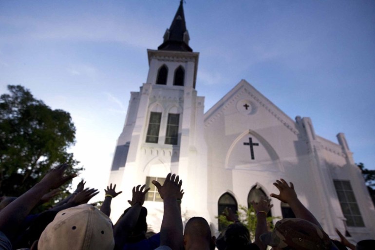 In this June 19, 2015 file photo, the men of Omega Psi Phi Fraternity Inc. lead a crowd of people in prayer outside the Emanuel AME Church, after a memorial for the nine people killed by Dylann Roof i