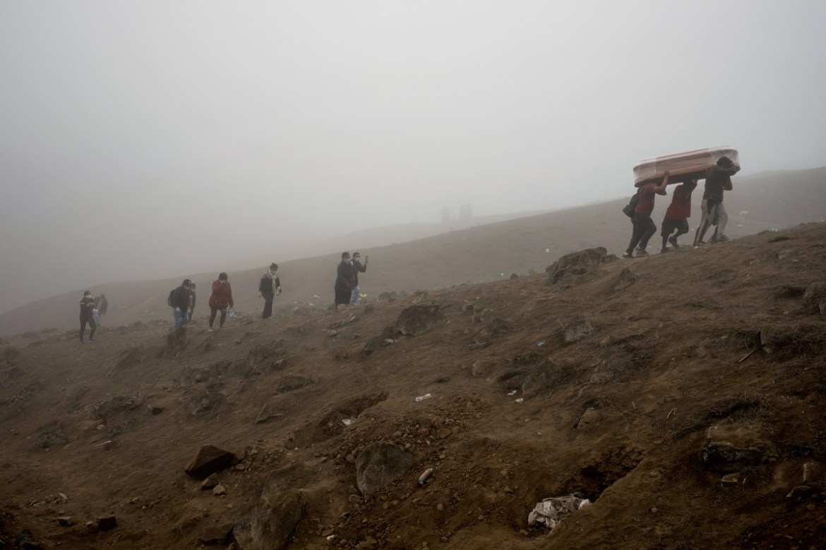 Cemetery workers carry the remains of Flavio Juarez, 50, who died of COVID-19, up the hill at the Nueva Esperanza cemetery on the outskirts of Lima, Peru, Tuesday, May 26, 2020. (AP Photo/Rodrigo Abd)
