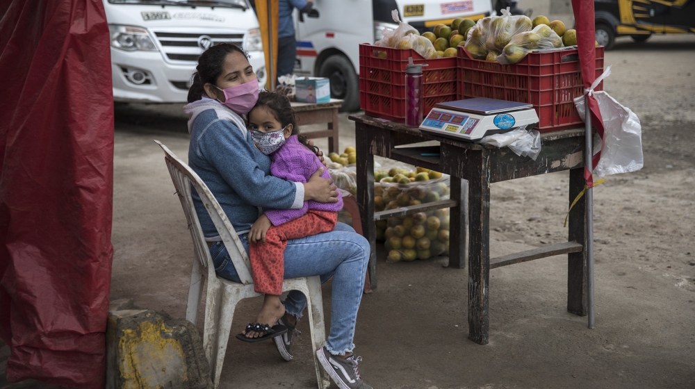 Wearing a mask to prevent the spread of the new coronavirus, Maria Garcia embraces her daughter Sofia, while selling oranges on a street in Lima, Peru, Thursday, June 4, 2020. (AP Photo/Rodrigo Abd)