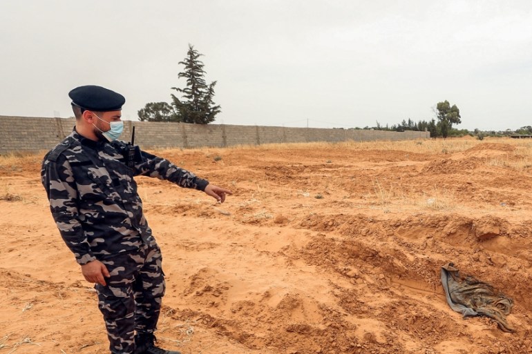 A member of security forces affiliated with the Libyan Government of National Accord (GNA)''s Interior Ministry points at the reported site of a mass grave in the town of Tarhuna, about 65 kilometres s