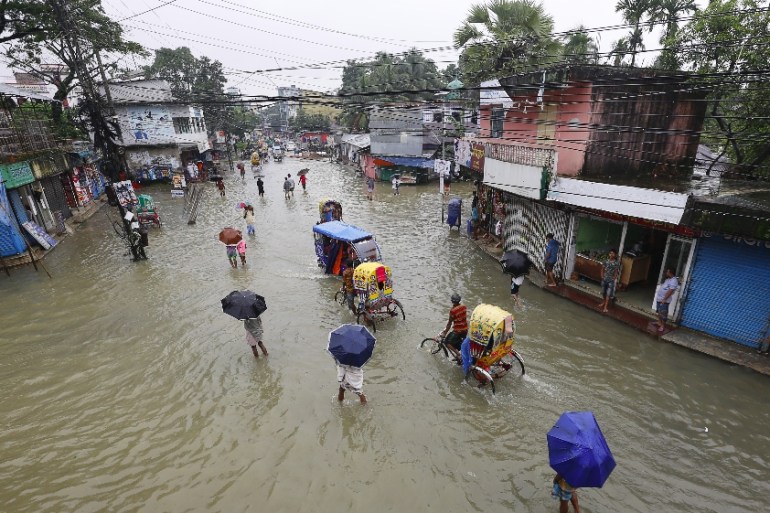 BANGLADESH-FLOOD-WEATHER In this photograph taken on July 12, 2020, people make their way through flood waters in Sunamgong. Sultan Mahmud / AFP