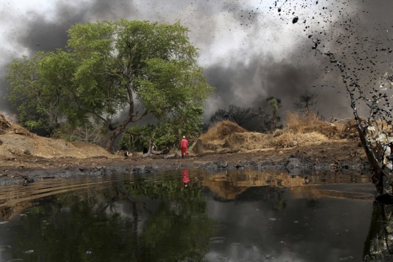 A man walks as crude oil spills from a pipeline in Dadabili, Niger state