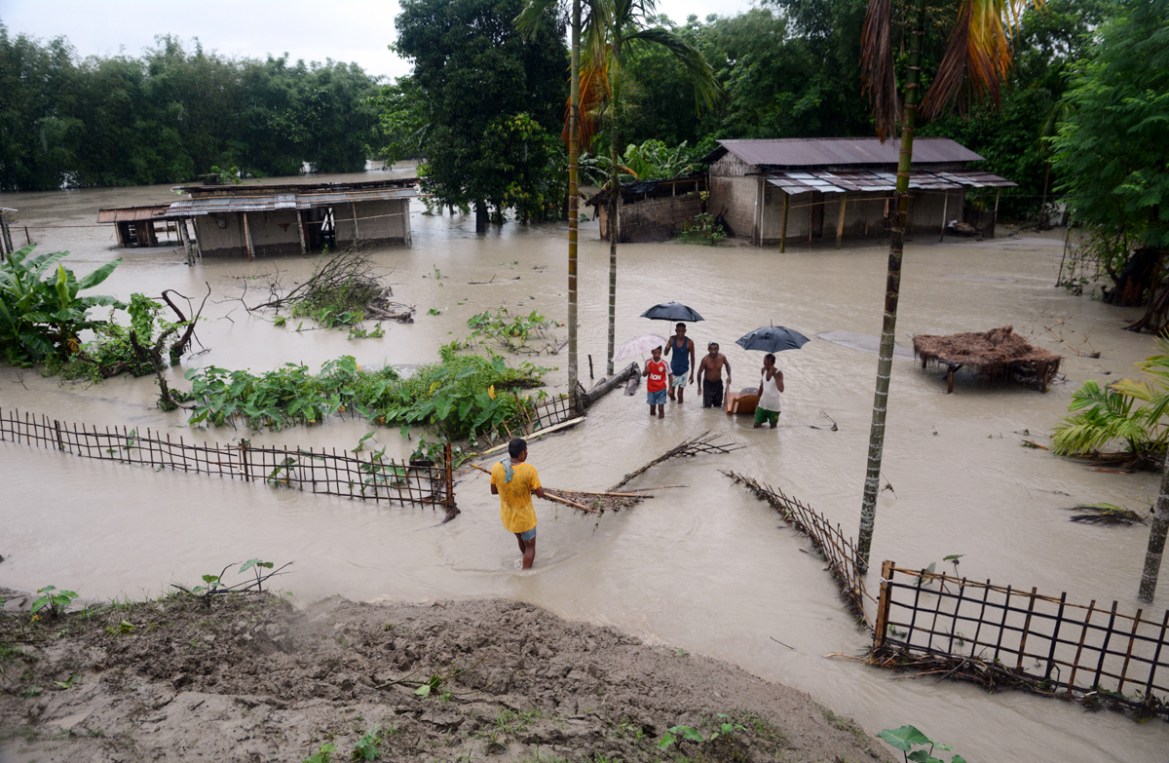 epa08541774 Villagers wade through the flood water at Pathsala in Barpeta district of Assam, India, 12 July 2020. Heavy rainfall during the past days has flooded many villages in the state, leaving ov