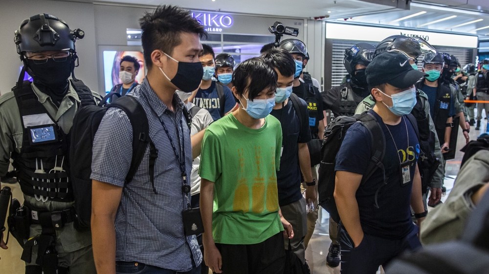 Police take away a man (C) during a demonstration in a mall in Hong Kong on July 6, 2020, in response to a new national security law introduced in the city which makes political views, slogans and sig