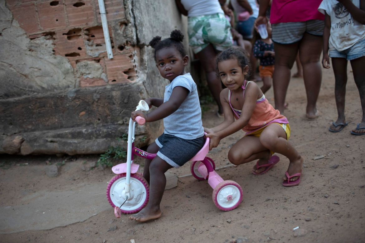 Children play as the adults collect donated food, cleaning supplies, and protective face masks amid the new coronavirus pandemic at the Maria Joaquina Quilombo in Cabo Frio on the outskirts of Rio de